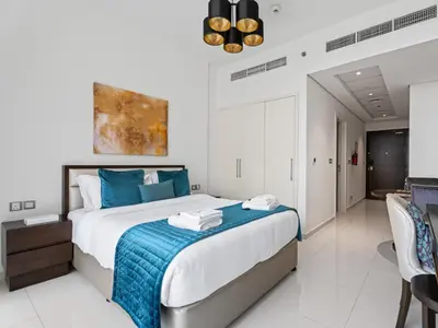 a bedroom with a large bed with blue pillows at Relaxing Stay Studio in Ghalia 29 in Dubai