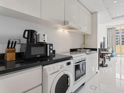 a white kitchen with a washer and dryer in it at Relaxing Stay Studio in Ghalia 29 in Dubai