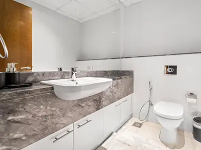 a white bathroom with a sink and a toilet at Charming City View w 1BDR Apartment In Noura Tower in Dubai