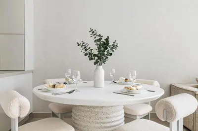 a white table with chairs and a white vase with flowers at 2BR plus M CF7 B Partial Canal View in Dubai