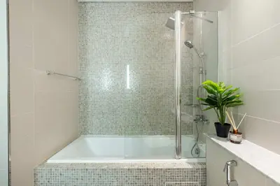 a bathroom with a tub with a glass shower at Silkhaus Entrepreneur Work & Stay Studio in DIFC in Dubai