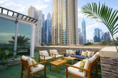 a patio with a blue couch and chairs and a city at Teremok Holiday Homes in Dubai