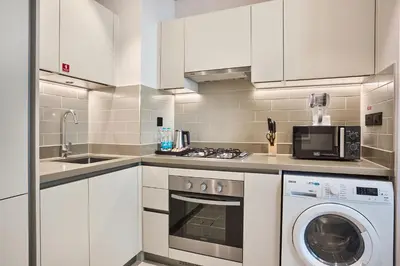 a kitchen with white cabinets and a washer and dryer at STAY BY LATINEM Luxury 1BR Holiday Home CV A 907 near Dubai Mall in Dubai