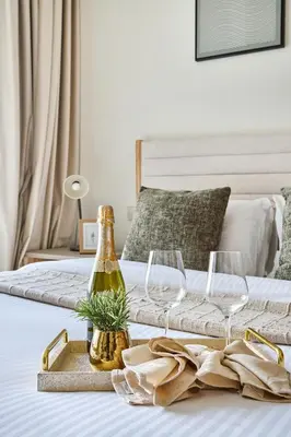 a bed with a bottle of champagne and two wine glasses at Frank Porter - Palace Beach Residence in Dubai