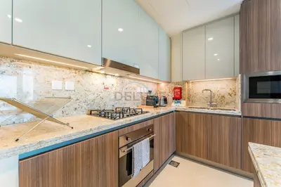 a kitchen with wooden cabinets and a stove top oven at High-Floor Balcony with Burj Khalifa View and Assistant Room, Minutes from Burj Plaza & Dubai Mall, Easy Access to Downtown Attractions, Imperial Avenue, Downtown Dubai by Deluxe Holiday Homes in Dubai