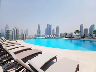 a swimming pool with lounge chairs and a city skyline at High-Floor Balcony with Burj Khalifa View and Assistant Room, Minutes from Burj Plaza & Dubai Mall, Easy Access to Downtown Attractions, Imperial Avenue, Downtown Dubai by Deluxe Holiday Homes in Dubai