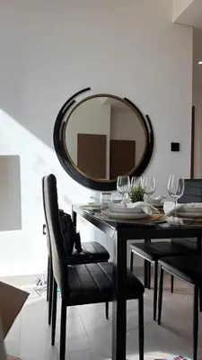 a dining room with a table and a mirror at Sleeps 4 I Circle Mall I Epic Pool in Dubai