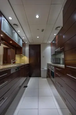 a large kitchen with wooden cabinets and white tile floors at Downtown 1BHK apartment with City view in Dubai