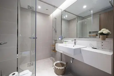 a bathroom with a sink and a glass shower at Canal Front Luxe, Elegant 2BR with Water Views in Dubai