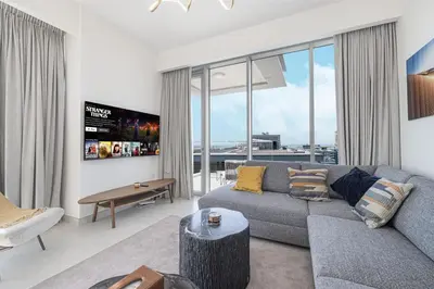 a living room with a gray couch and large windows at Canal Front Luxe, Elegant 2BR with Water Views in Dubai