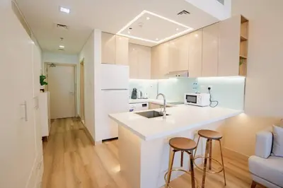 a kitchen with a sink and two bar stools at Sunny Studio - Dubai Marina - Close Beach in Dubai