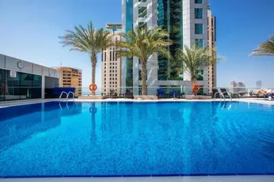 a large swimming pool with palm trees and buildings at Sunny Studio - Dubai Marina - Close Beach in Dubai