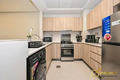 a kitchen with a refrigerator and a dishwasher at Oversized 1BR Apartment Near Dubai Hills Mall in Dubai