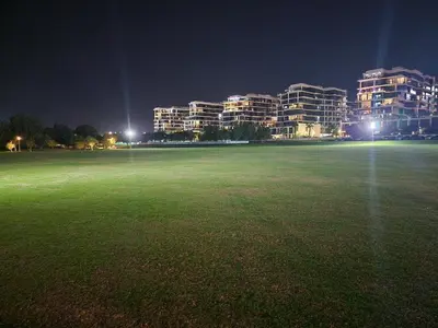 a field with buildings in the background at night at Spacious Golf & Pool View Home with Huge Balcony in Dubai