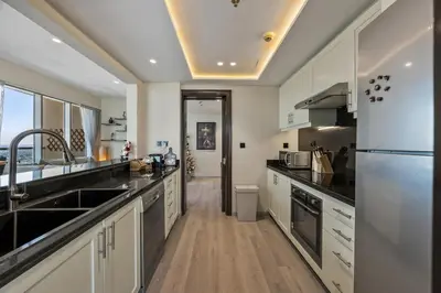 a large kitchen with a sink and a refrigerator at Nonna house Stylish 1BR and Panoramic Studio, City, Golf, Lake view in Dubai