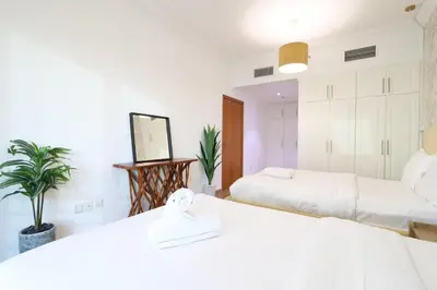 a white bedroom with two beds and a mirror at Luxury 2BHK In Marina W Rooftop Pool Man 1908 in Dubai