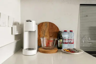 a kitchen counter with a blender and bottles of water at New Elegant 1BR with Balcony & Pool in Park Field in Dubai