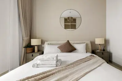 a bedroom with a large white bed with a mirror at New Elegant 1BR with Balcony & Pool in Park Field in Dubai
