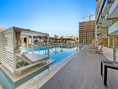 a view of a swimming pool with a table and a building at New! Lovely 1BR with Balcony & Pool in Binghatti Orchid in Dubai