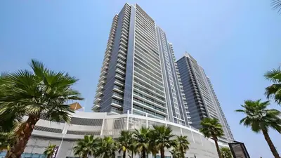 a tall building with palm trees in front of it at Studio in Dubai