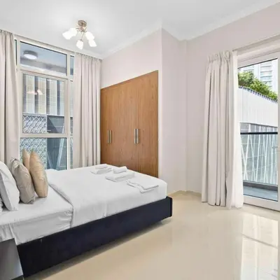 a white bedroom with a large bed and a window at Dunya Tower in Dubai