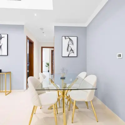 a dining room with a glass table and white chairs at Dunya Tower in Dubai