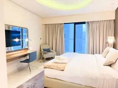 a bedroom with a large bed and a desk with a television at Cozy 2BR in Paramount Dubai with Burj Khalifa View in Dubai