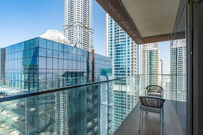a chair on a balcony with a view of a city at PVH - Marina Gate 2 - Harmonious 2BR with Sea View in Dubai