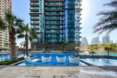 a swimming pool with white chairs and a tall building at PVH - Marina Gate 2 - Harmonious 2BR with Sea View in Dubai