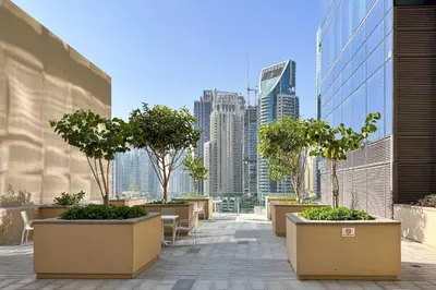 a balcony with tables and trees and a city skyline at PVH - Marina Gate 2 - Harmonious 2BR with Sea View in Dubai