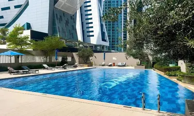 a large blue swimming pool with buildings in the background at 1BR Canal Views Large Balcony Spacious BusinessBay in Dubai