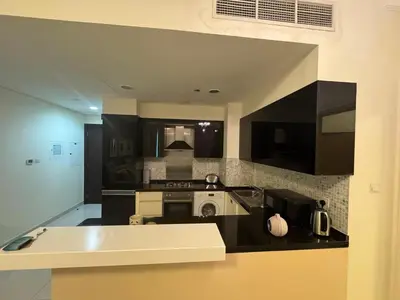 a kitchen with black cabinets and a stove top oven at Damac Maison mall street in Dubai