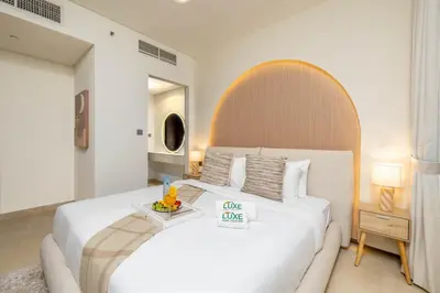 a white bedroom with a large white bed and a table at Sky Gardens By Luxe Living Collection - Duplex 2BR - DIFC in Dubai