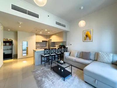 a living room with a couch and a kitchen at Werova- Waterfront 1-Bedroom Apartment Furnished in Dubai