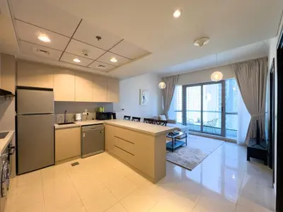 a large kitchen with a counter and a dining room at Werova- Waterfront 1-Bedroom Apartment Furnished in Dubai