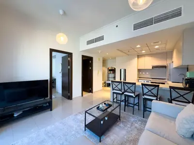 a living room with a couch and a tv and a kitchen at Werova- Waterfront 1-Bedroom Apartment Furnished in Dubai