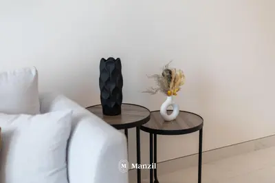 two tables with vases and a couch in a living room at 1BR Urban Living near Downtown in District One in Dubai