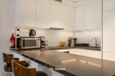 a kitchen with white cabinets and a stainless steel counter top at 1BR Urban Living near Downtown in District One in Dubai