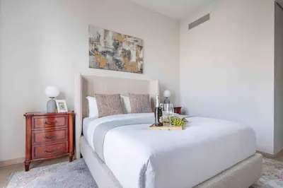 a bedroom with a white bed and a wooden dresser at Frank Porter - Grande Signature in Dubai