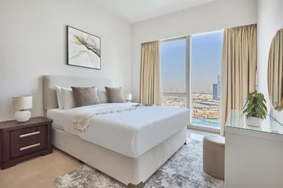a white bedroom with a large bed and a large window at Frank Porter - Grande Signature in Dubai