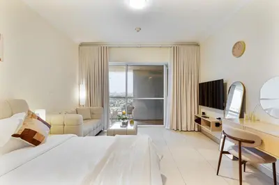 a white bedroom with a large bed and a desk at Stylish JLT Studio in Dubai