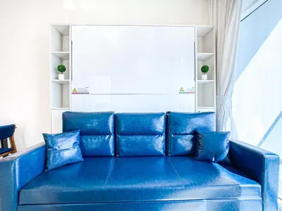 a blue couch in a room with a window at Chic Urban Escape 1BR Sleeps- 4 In Bayz-18 in Dubai