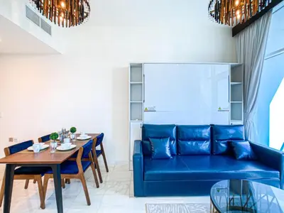 a living room with a blue couch and a table at Chic Urban Escape 1BR Sleeps- 4 In Bayz-18 in Dubai