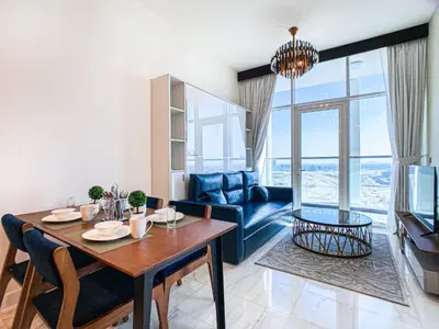 a living room with a table and a blue couch at Chic Urban Escape 1BR Sleeps- 4 In Bayz-18 in Dubai