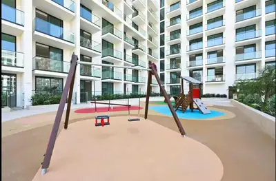 a playground in front of a large building at Vogue JVC Binghatti Phoenix near Circle Mall, One Bedroom Apartment with Balcony and Access to all Amenities in Dubai
