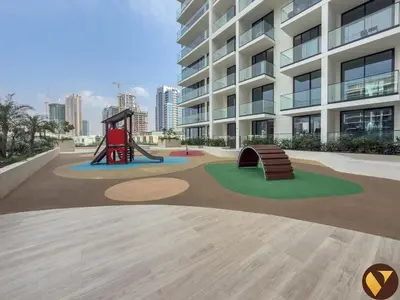 a playground in front of a large building at Vogue JVC Binghatti Phoenix near Circle Mall, One Bedroom Apartment with Balcony and Access to all Amenities in Dubai