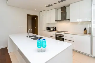 a white kitchen with two water bottles on a counter at Elegant 2BR with Maids Room City Walk in Dubai