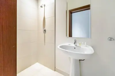 a white bathroom with a sink and a shower at Elegant 2BR with Maids Room City Walk in Dubai