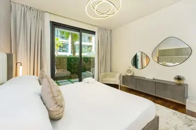 a white bedroom with a large bed and a mirror at Elegant 2BR with Maids Room City Walk in Dubai