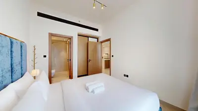 a white bedroom with a large white bed and a room at Vacationer l Elegant 1 Bedroom l Near to Park and Mall l JVC in Dubai